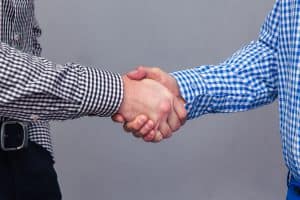 Portrait of a two male hands doing handshake over gray background