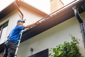 Man cleaning roof gutter leaves