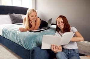 Two,Female,College,Students,In,Shared,House,Bedroom,Studying,Together