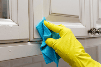 Hand cleaning cupboard door Shutterstock_1907712061